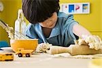 Little boy rolling out dough with rolling pin