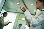 Woman holding powder compact putting on makeup, low angle view