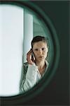 Woman using cell phone seen through door window