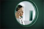 Woman using cell phone, viewed through window