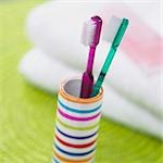 two toothbrushes in a striped beaker
