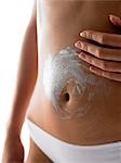 Woman putting cream on belly