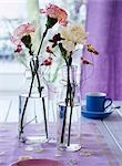 Carnations in glass bottles decorated with artificial birds