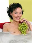 Woman with green grapes in bathtub