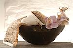 Massage belt and heart-shaped soap decorated with flowers in a wooden bowl