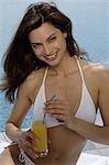 Woman in bikini with a drink at the swimming pool