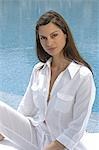 Woman dressed in white sitting at the swimming pool