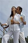 A couple dressed in white is enjoying a drink