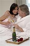 Couple in bed drinking sparkling wine