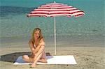 Woman sitting on the beach under a sunshade