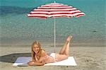 Femme allongée sur la plage sous un parasol