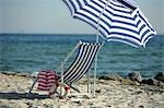 Blue and white sunshade and deckchair on the beach