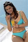 Woman in bikini drinking orange juice at the swimming pool