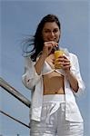 Woman dressed in white enjoying a drink at the swimming pool