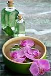 Orchid blossoms in a water bowl and small bottle for perfume