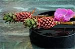 Arangement of bromelia,orchid blossom and a water bowl