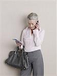 Senior adult in business clothing using mobile phone