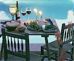 Table de salle à manger en bord de piscine avec vin, fromage, pain, raisins et aux chandelles