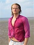 Young man with lila shirt on the beach