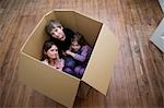 Trois enfants assis à l'intérieur d'une boîte.