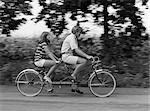 1970s TEENAGE GIRL AND BOY RIDING BICYCLE BUILT FOR TWO