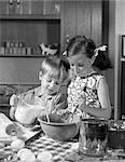 1960s TWO CHILDREN MIXING POURING BAKING IN KITCHEN