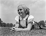 ANNÉES 1940 ENFANT COUCHÉ SUR L'HERBE SOURIANT