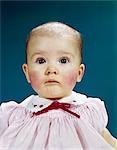 1960s PORTRAIT BABY GIRL SAD FACIAL EXPRESSION RED BOW AT COLLAR