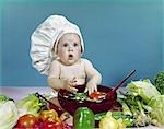 1960s BABY WEARING CHEF HAT ABOUT TO TOSS SALAD WITH HANDS WOODEN SALAD BOWL FRESH VEGETABLES INGREDIENTS