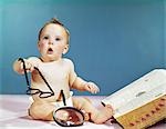 1960s BABY HOLDING EYEGLASSES WITH OPEN DICTIONARY AND MAGNIFYING GLASS RESEARCH