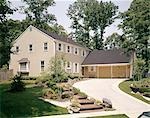1970s TWO STORY YELLOW HOUSE WHITE SHUTTERS WITH TWO CAR GARAGE CURVED DRIVEWAY LANDSCAPED LAWN SUBURBAN
