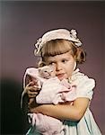 1950s 1960s LITTLE GIRL IN EASTER HAT HUGGING A KITTEN STUDIO