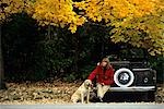 FILLE ASSISE SUR LE PARE-CHOCS DE VOITURE AVEC CHIEN