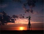 SILHOUETTE WINDMILL ON FARM AT SUNSET