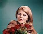 1960s BLOND WOMAN WEARING FUR COAT HOLDING BUNCH OF RED ROSES