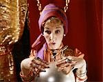 ANNÉES 1960 FEMME GITANE FORTUNE TELLER REGARDANT DANS LA BOULE DE CRISTAL