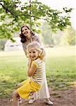 1970s SMILING WOMAN MOTHER WITH GIRL DAUGHTER SWINGING PLAYING ON ROPE SWING