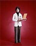 1970s WOMAN DOCTOR FULL LENGTH PORTRAIT STANDING HOLDING PATIENT CHART
