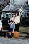 ANNÉES 1980 FAMILLE MÈRE PÈRE FILS ONDULER AU REVOIR UN CHARGEMENT BAGAGES DANS LA VOITURE