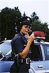 1970s POLICE WOMAN TALKS ON WALKIE-TALKIE BY POLICE CAR