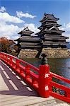 RED FOOTBRIDGE LEADING TO MATSUMOTO CASTLE IN AUTUMN JAPAN