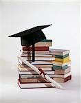 1970s GRADUATION STILL LIFE OF DIPLOMA AND MORTARBOARD ON TOP OF PILE STACK OF BOOKS