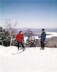 1960s COUPLE MAN WOMAN SKIERS TOP HILL