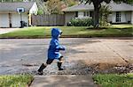 Boy Walking through Puddles on Street