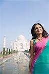 Frau lächelnd mit einem Mausoleum in den Hintergrund, Taj Mahal, Agra, Uttar Pradesh, Indien