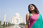 Frau lächelnd mit einem Mausoleum in den Hintergrund, Taj Mahal, Agra, Uttar Pradesh, Indien
