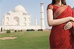 Mid section view of a woman standing in front of a mausoleum, Taj Mahal, Agra, Uttar Pradesh, India