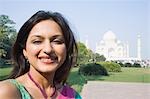 Gros plan d'une femme souriante avec un mausolée dans le fond, Taj Mahal, Agra, Uttar Pradesh, Inde