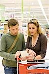 Couple with shopping cart reviewing receipt