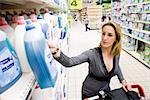 Woman selecting bottle of detergent from supermarket shelf